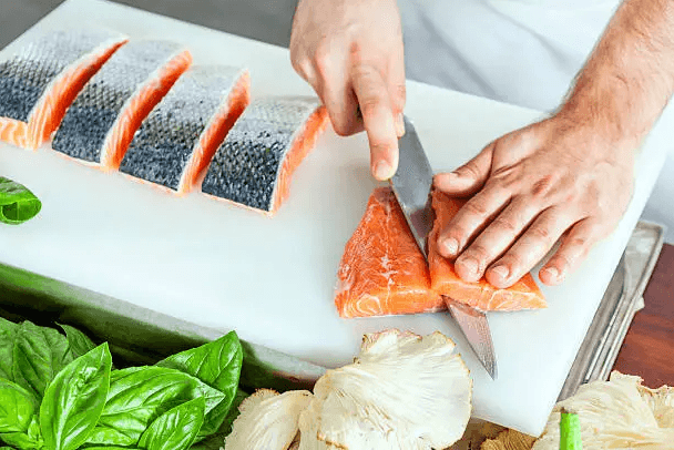 Perfectly cooked salmon fillet from frozen in an air fryer, garnished with lemon slices and fresh herbs.