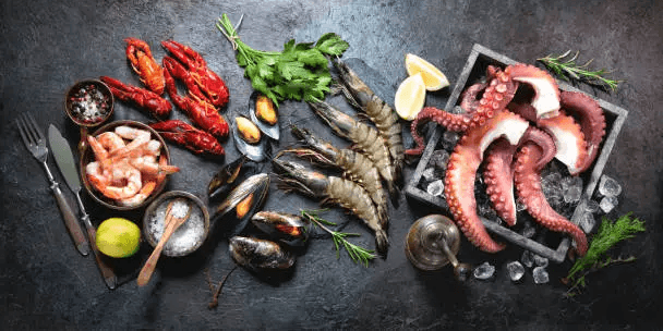 Freshly prepared seafood platter featuring lobster, shrimp, oysters, and salmon served on a bed of ice with lemon wedges and dipping sauces.