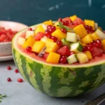 A bowl of vibrant Hwachae featuring watermelon chunks, grapes, and mint leaves in a hollowed-out watermelon.