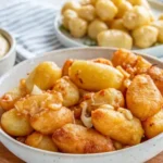 A plate of golden-fried cheese curds served with dipping sauces on a rustic wooden table.