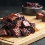 Close-up of glazed burnt end BBQ pieces on a wooden board