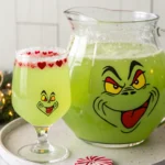 Bright green Grinch Punch in a clear punch bowl with lime sherbet and red sugar rimmed glasses.