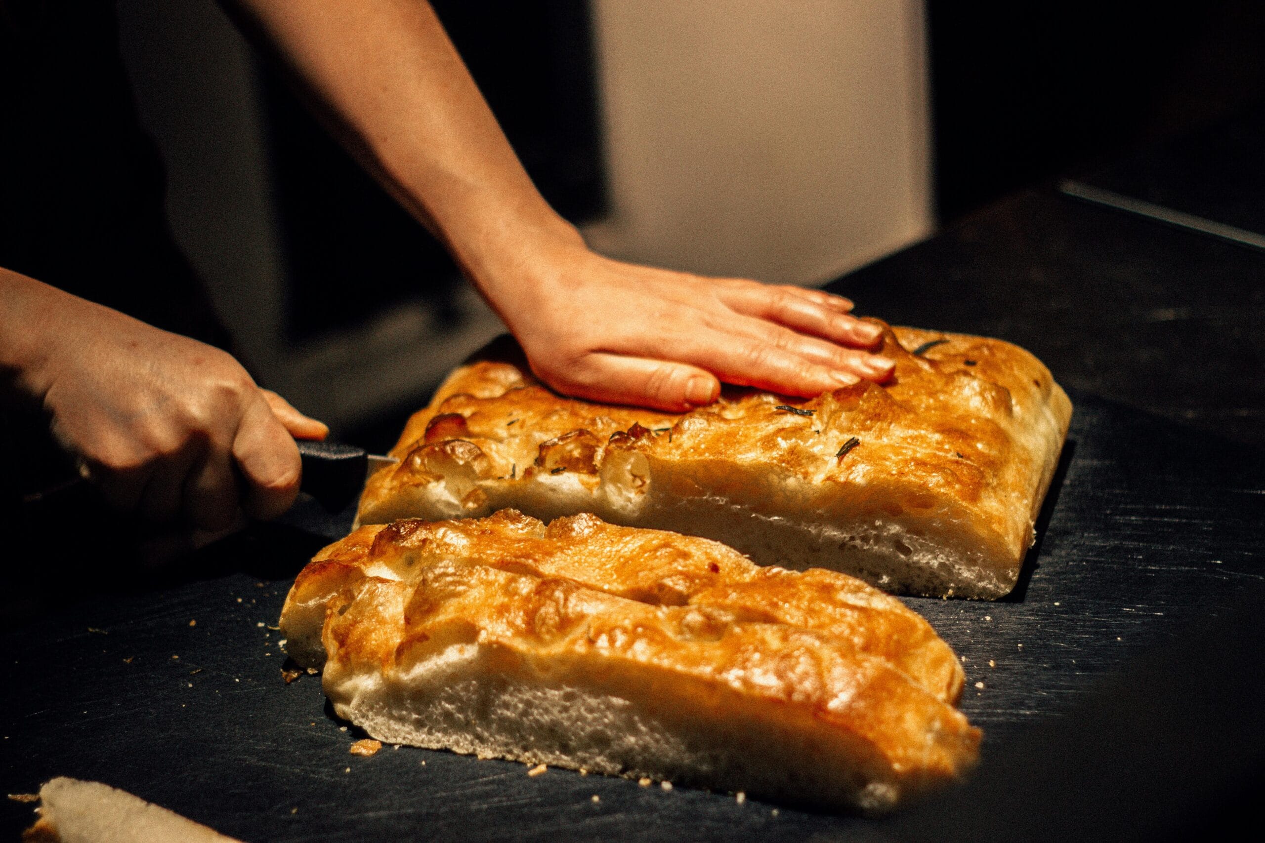 Freshly baked Amish Apple Fritter Bread on a rustic wooden table, with layers of spiced apples, a golden-brown crust, and a drizzle of cinnamon glaze, surrounded by fresh apples and cinnamon sticks.