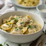 Creamy chicken tortellini alfredo garnished with parsley on a white plate.