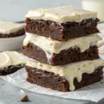 Fudgy brownies with cream cheese frosting topped with chocolate shavings.